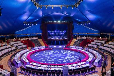 Personnes dansant sous des éclairages colorés dans une salle sombre avec des gradins en arrière-plan.