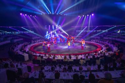 Personnes dansant sous des éclairages colorés dans une salle sombre avec des gradins en arrière-plan.