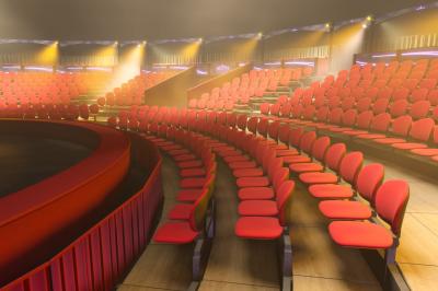 Salle de spectacle circulaire avec gradins éclairés par des lumières violettes et une scène centrale.
