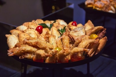 Buffet avec plats variés, incluant viandes grillées garnies de citron et légumes frais en présentation colorée.