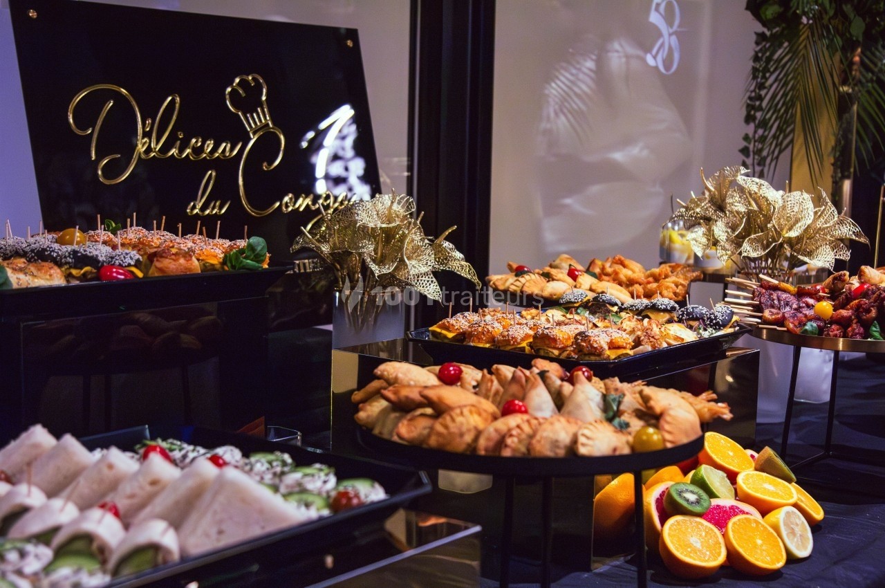 Buffet varié avec viennoiseries, fruits frais, sandwichs et décorations dorées dans un cadre élégant.