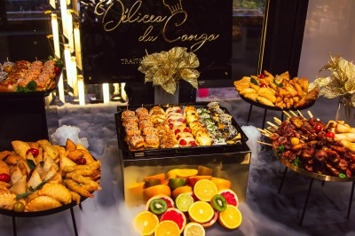 Buffet avec plats variés, incluant viandes grillées garnies de citron et légumes frais en présentation colorée.