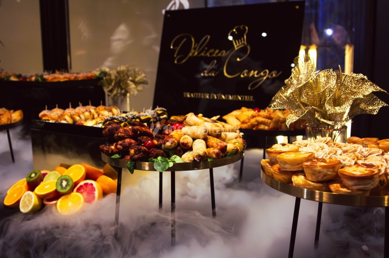 Buffet de mets variés comprenant fruits, brochettes, feuilletés et autres plats, présenté sur des plateaux élégants.