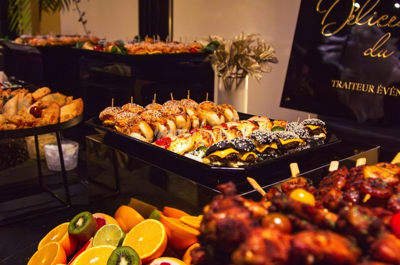 Buffet varié avec brochettes, fruits frais et amuse-bouches présentés sur des plateaux élégants.