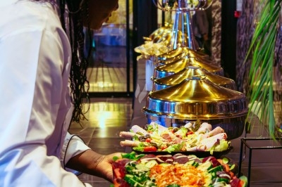 Buffet avec plats variés, incluant viandes grillées garnies de citron et légumes frais en présentation colorée.