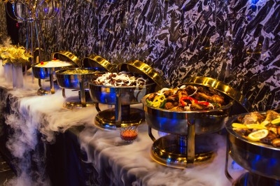 Buffet avec plats variés, incluant viandes grillées garnies de citron et légumes frais en présentation colorée.