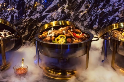 Buffet avec plats variés, incluant viandes grillées garnies de citron et légumes frais en présentation colorée.