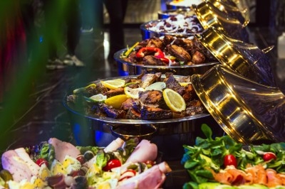 Buffet avec plats variés, incluant viandes grillées garnies de citron et légumes frais en présentation colorée.