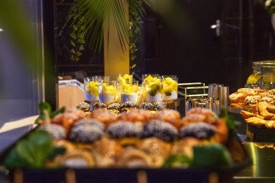 Buffet varié avec plats de viande grillée, légumes frais et charcuterie, présenté dans des plats en métal.