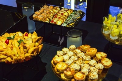 Buffet varié avec plats de viande grillée, légumes frais et charcuterie, présenté dans des plats en métal.