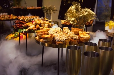 Buffet varié avec plats de viande grillée, légumes frais et charcuterie, présenté dans des plats en métal.