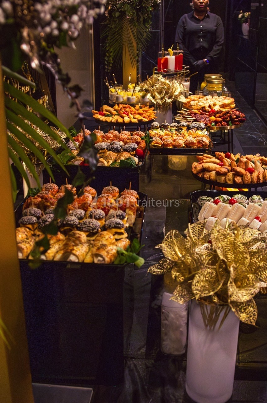 Buffet élégant avec une variété de pâtisseries, de sandwichs et de décorations dorées dans un cadre raffiné.
