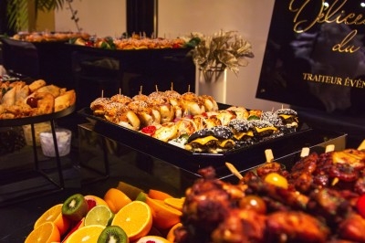 Buffet varié avec plats de viande grillée, légumes frais et charcuterie, présenté dans des plats en métal.