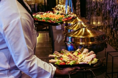 Buffet varié avec plats de viande grillée, légumes frais et charcuterie, présenté dans des plats en métal.