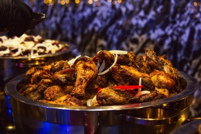 Buffet varié avec plats de viande grillée, légumes frais et charcuterie, présenté dans des plats en métal.