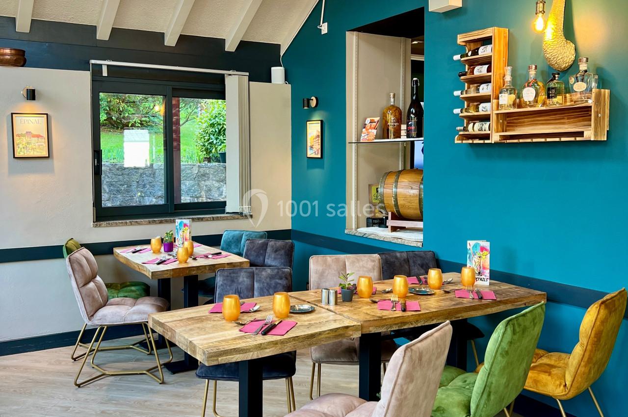 Salle de restaurant lumineuse avec tables en bois, chaises colorées et décoration murale moderne.
