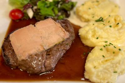 Cabane en bois enneigée avec un feu allumé à l'intérieur, vue de nuit dans un paysage hivernal.