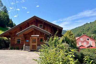 Cabane en bois enneigée avec un feu allumé à l'intérieur, vue de nuit dans un paysage hivernal.