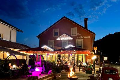 Cabane en bois enneigée avec un feu allumé à l'intérieur, vue de nuit dans un paysage hivernal.