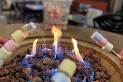 Cabane en bois enneigée avec un feu allumé à l'intérieur, vue de nuit dans un paysage hivernal.