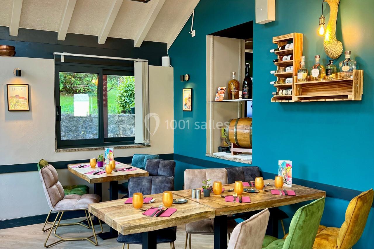 Salle de restaurant lumineuse avec tables en bois, chaises colorées et décoration murale chaleureuse.