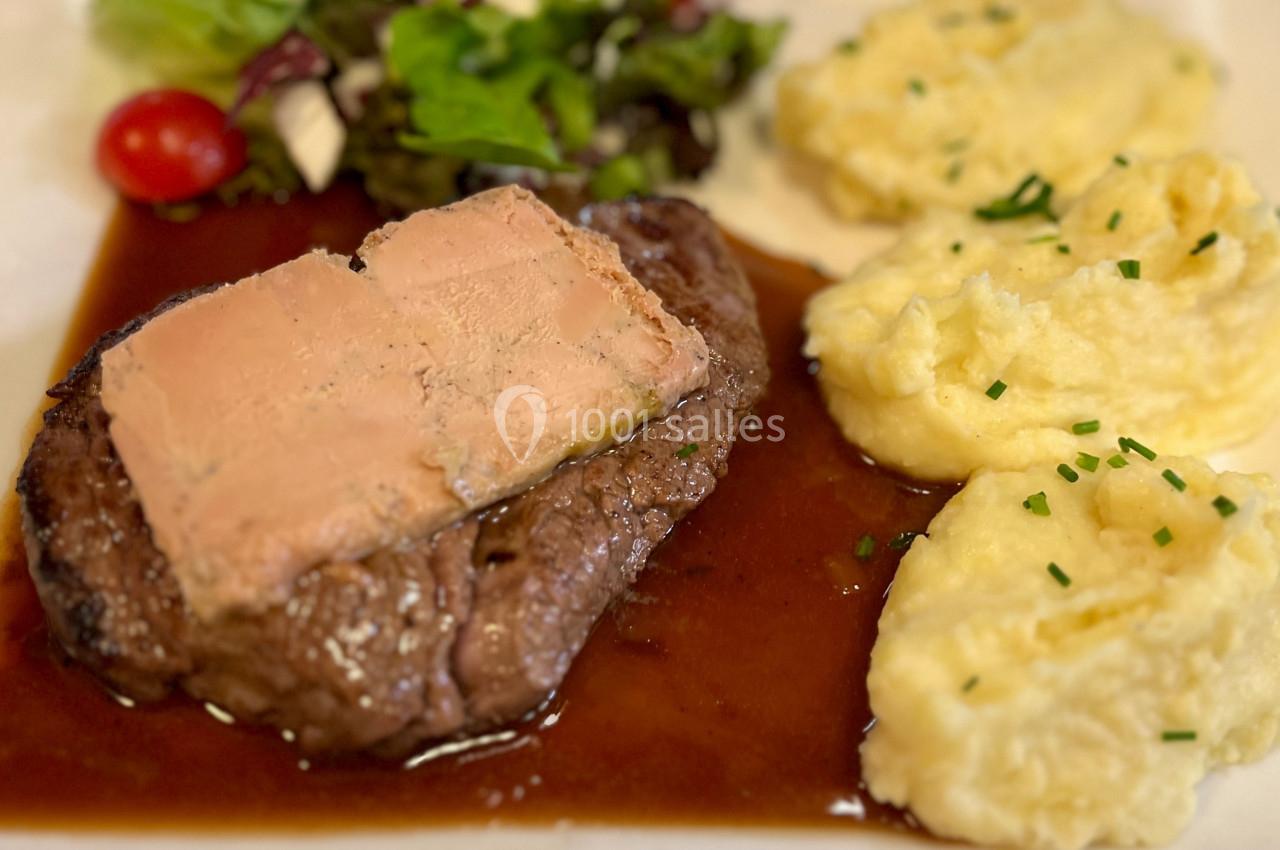 Plat composé d'un steak surmonté de foie gras, accompagné de purée de pommes de terre et d'une salade verte.