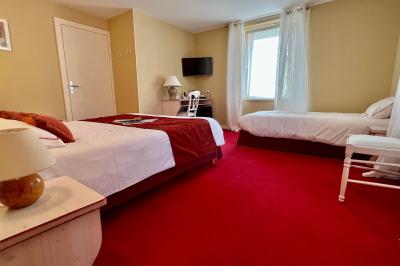 Chambre lumineuse avec un lit double, un lit simple, des tables de chevet et un tableau encadré au mur.