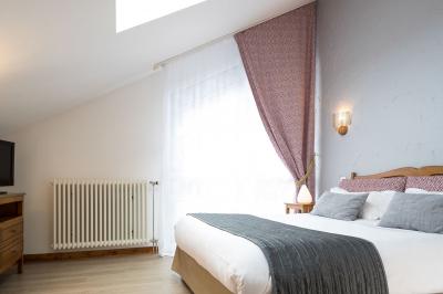 Chambre lumineuse avec un lit double, un lit simple, des tables de chevet et un tableau encadré au mur.