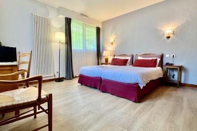 Chambre lumineuse avec un lit double, un lit simple, des tables de chevet et un tableau encadré au mur.