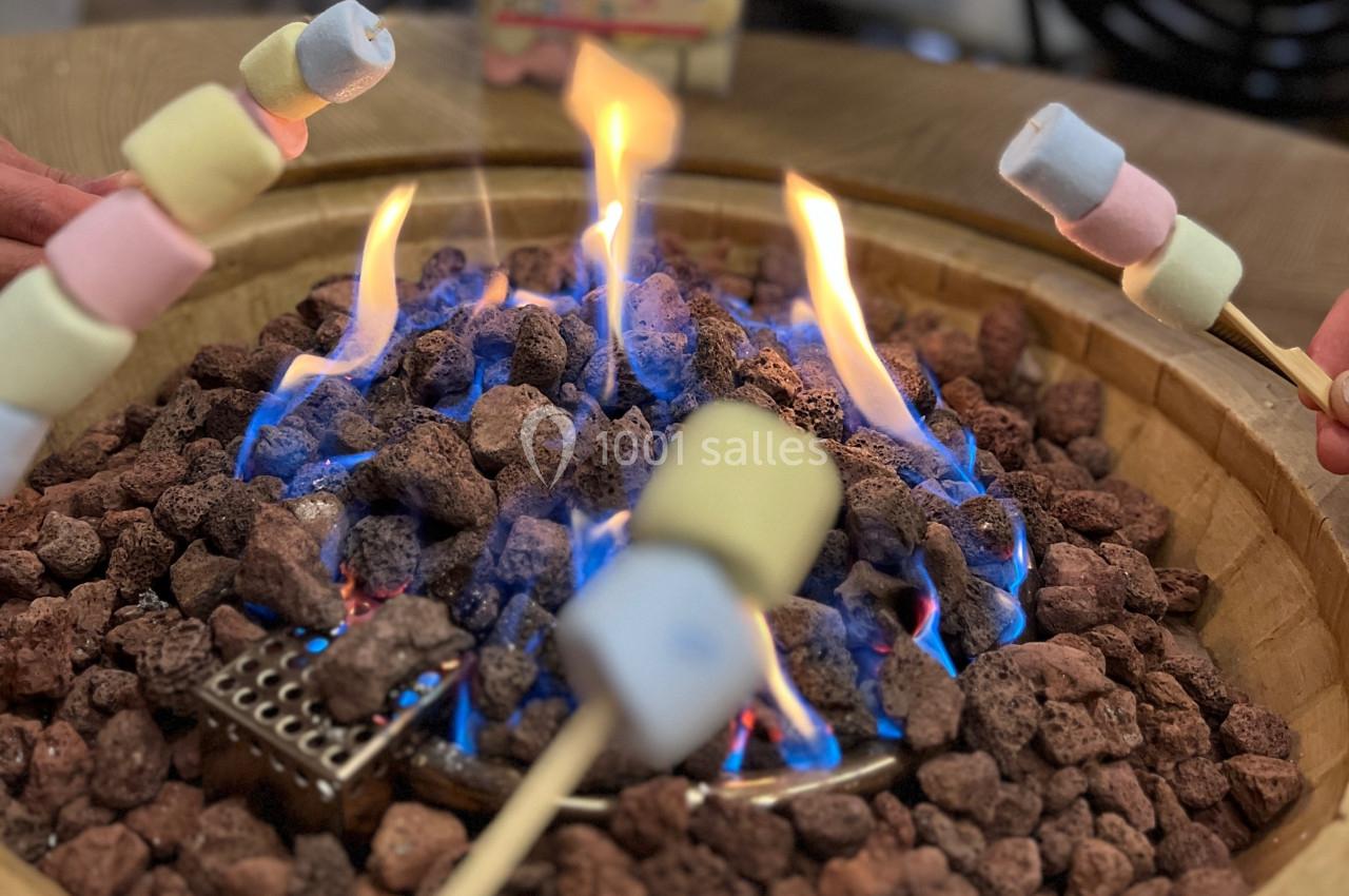 Des guimauves colorées sont grillées sur des brochettes au-dessus d'un feu de pierres volcaniques.