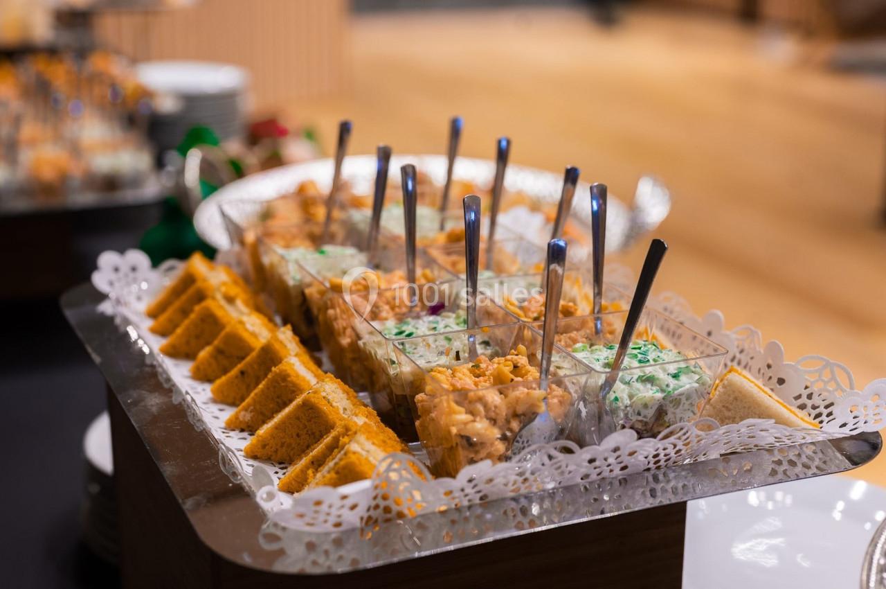 Plateau de verrines variées et tranches de cake salé disposés sur une table lors d'un buffet.