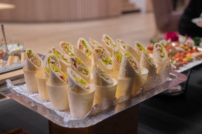 Assortiment de wraps garnis de légumes et de poulet, entourés de petits pains et de sandwichs sur un plateau.