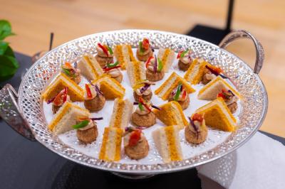 Assortiment de wraps garnis de légumes et de poulet, entourés de petits pains et de sandwichs sur un plateau.