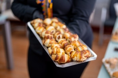 Assortiment de wraps garnis de légumes et de poulet, entourés de petits pains et de sandwichs sur un plateau.