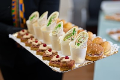 Assortiment de wraps garnis de légumes et de poulet, entourés de petits pains et de sandwichs sur un plateau.