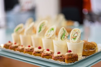 Assortiment de wraps garnis de légumes et de poulet, entourés de petits pains et de sandwichs sur un plateau.