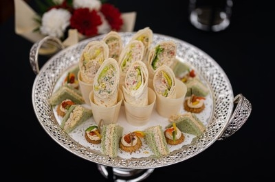 Assortiment de wraps garnis de légumes et de poulet, entourés de petits pains et de sandwichs sur un plateau.