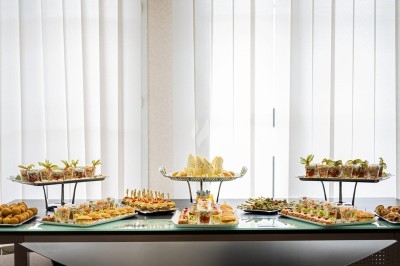 Assortiment de wraps garnis de légumes et de poulet, entourés de petits pains et de sandwichs sur un plateau.