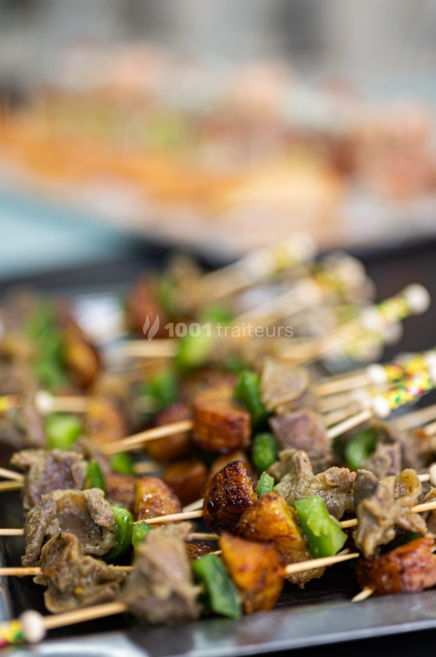 Brochettes de viande grillée avec morceaux de légumes et d'épices, présentées sur un plateau.