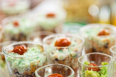 Assortiment de wraps garnis de légumes et de poulet, entourés de petits pains et de sandwichs sur un plateau.