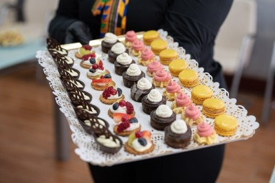 Plateau de mignardises variées comprenant macarons, mini-gâteaux au chocolat et desserts garnis de fruits rouges.
