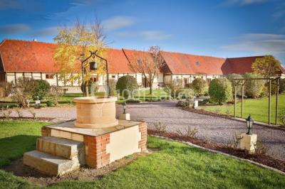 Salle de bain moderne avec douche vitrée, lavabo blanc, miroir, sèche-serviettes et poutres en bois apparentes.