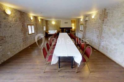 Salle de bain moderne avec douche vitrée, lavabo blanc, miroir, sèche-serviettes et poutres en bois apparentes.