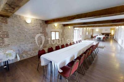 Salle de bain moderne avec douche vitrée, lavabo blanc, miroir, sèche-serviettes et poutres en bois apparentes.