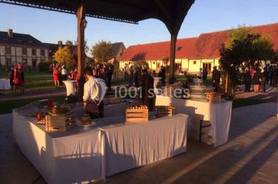 Salle de bain moderne avec douche vitrée, lavabo blanc, miroir, sèche-serviettes et poutres en bois apparentes.