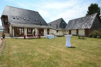 Salle de bain moderne avec douche vitrée, lavabo blanc, miroir, sèche-serviettes et poutres en bois apparentes.