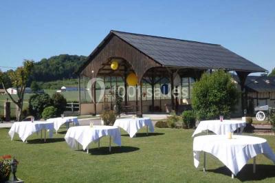 Salle de bain moderne avec douche vitrée, lavabo blanc, miroir, sèche-serviettes et poutres en bois apparentes.