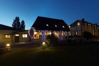 Salle de bain moderne avec douche vitrée, lavabo blanc, miroir, sèche-serviettes et poutres en bois apparentes.