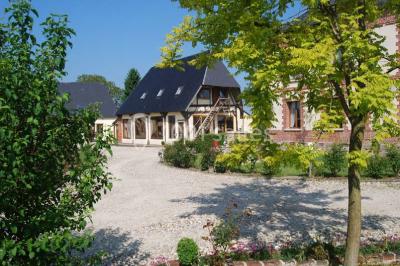 Salle de bain moderne avec douche vitrée, lavabo blanc, miroir, sèche-serviettes et poutres en bois apparentes.