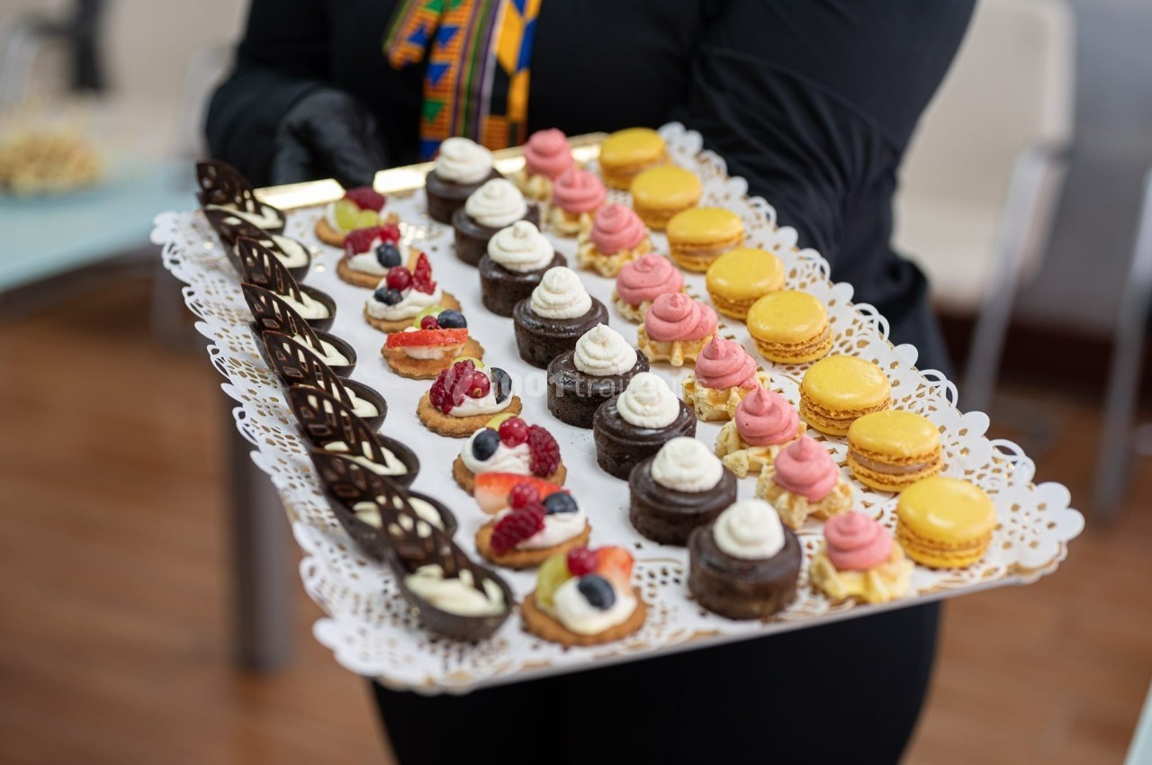 Plateau de mignardises variées comprenant macarons, mini-gâteaux au chocolat et desserts garnis de fruits rouges.